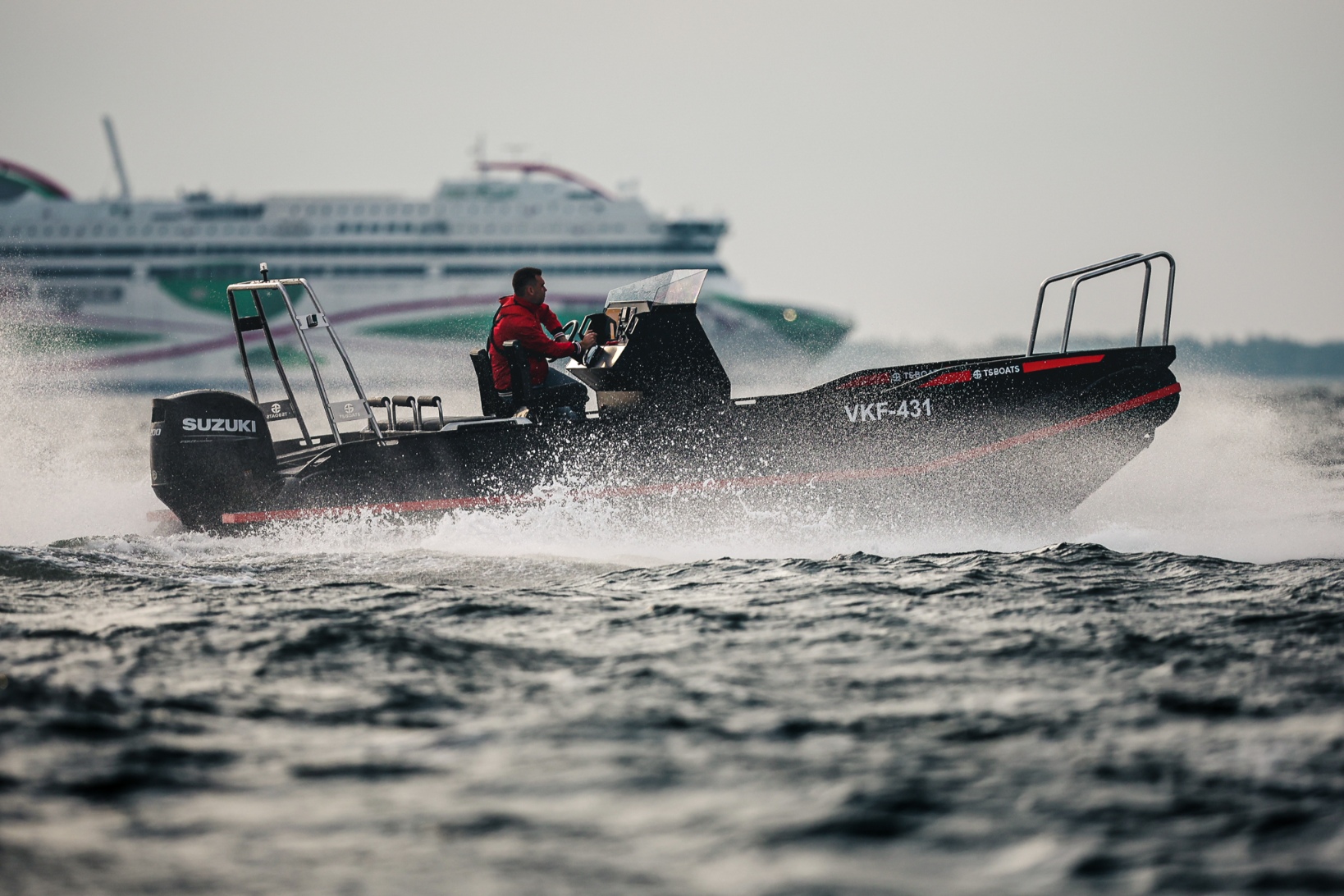 Dynamic image of a man piloting a black and red TS Boats plastic boat with a Suzuki outboard motor, cutting through the water at high speed